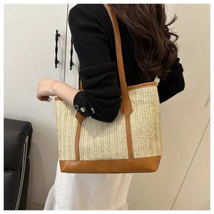 Gros plan d'un grand sac cabas en paille tissée avec anses en cuir marron porté