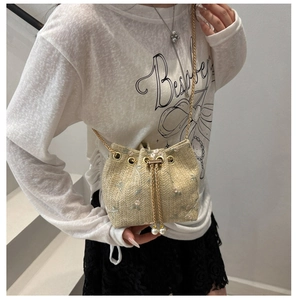Detail of floral embroidery and pearl drawstring on beige woven bucket bag with chain