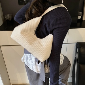 Minimalist beige woven hobo bag for women shown as a stylish shoulder bag on a model