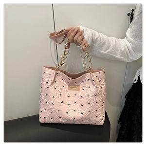 Detailed view of pink quilted tote bag with black bow patterns and gold chain strap