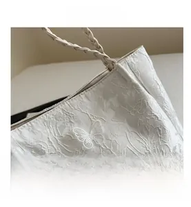 Detailed macro view of white lace butterfly embroidery and elegant tassel on the shoulder bag