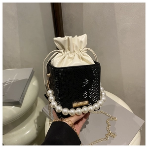 Detail of black snakeskin bucket bag with white drawstring and pearl handle ornament