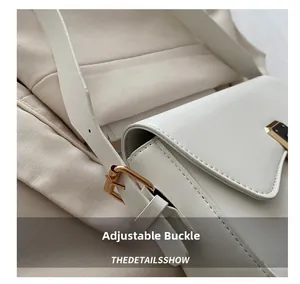 Detailed close-up of adjustable gold-tone buckle on white leather crossbody bag strap
