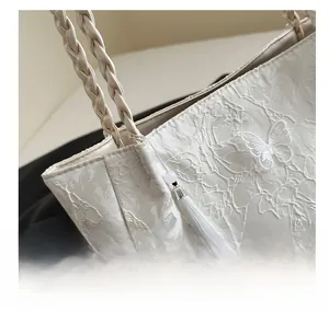 Detail of floral lace tote bag with butterfly embroidery and silk tassel charm