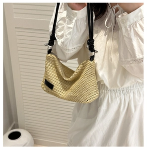 Détail d'un sac en paille tressée avec bandoulière en corde noire et boucle en métal
