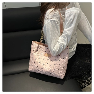 Detailed shot of pink quilted tote bag with black bows and gold chain handle decoration