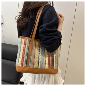 Gros plan du sac cabas tissé à rayures colorées avec anses et base en cuir marron