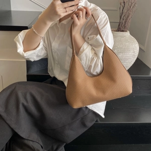 Brown woven hobo shoulder bag for women worn by a model in a minimalist indoor setting