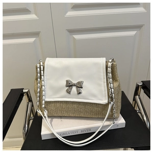 Detailed macro of woven straw material and silver bow metal clasp on shoulder bag