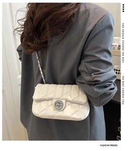 Petit sac blanc matelassé avec fermoir argenté porté par un mannequin en blazer