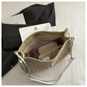 Detail of straw hobo bag with magnetic closure, silver chain strap, and interior space