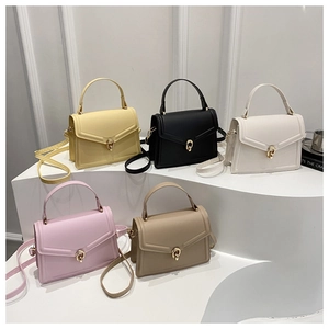 Detailed row of minimalist leather handbags in five soft colors on a white pedestal