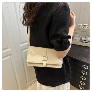Vue détaillée du sac bandoulière crème avec texture tissée, porté de côté arrière