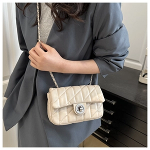 Détail d'un sac bandoulière beige matelassé avec fermoir rotatif argenté et chaîne