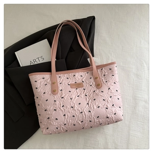 Detailansicht der rosa Shopper-Tasche mit Bubble-Textur, Schleifenprint und goldenem Logo