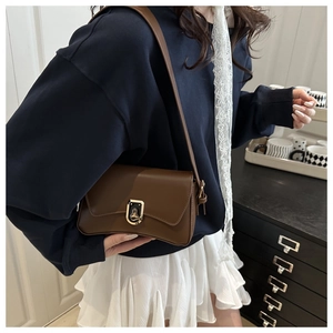 Brown leather crossbody bag with gold metal lock closure shown on female model