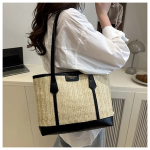 Détail du cabas en paille tressée avec anses en cuir noir et texture beige chic