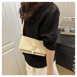 Détail d'un sac à bandoulière crème minimaliste avec texture tissée et boucle carrée