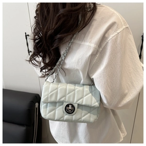 Détail du sac en cuir matelassé bleu clair avec bandoulière chaîne et fermoir rotatif
