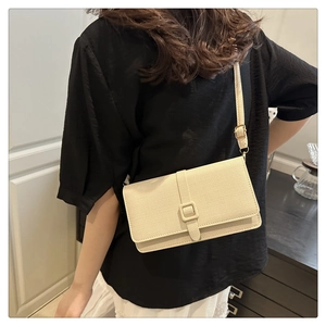 Détail du sac bandoulière minimaliste crème avec tissu texturé et boucle carrée élégante