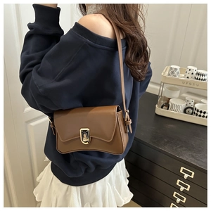 Brown retro underarm bag with gold twist lock shown in a casual lifestyle setting