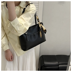 Detail of black PU leather tote bag with white contrast stitching and silk scarf accessory