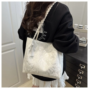 Detailed view of white lace tote bag with floral butterfly embroidery and rope strap