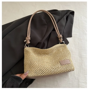 Détail du sac bandoulière en paille avec texture tissée fine et écusson en cuir griffé