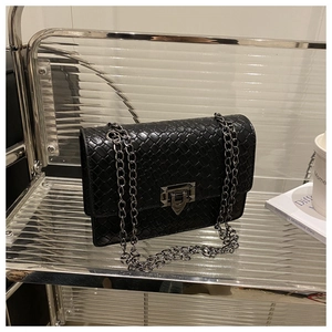 Close-up of black woven leather bag with silver geometric buckle and chain strap