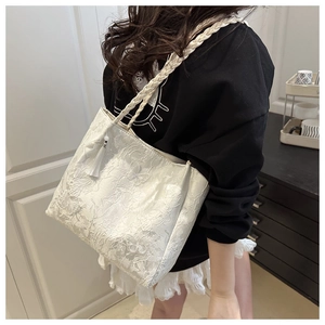 Detail of white lace tote bag with floral embroidery and bohemian tassel decoration