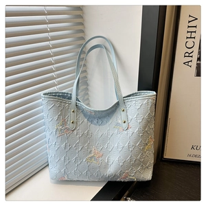 Détail du sac cabas bleu clair avec motif matelassé et broderie de papillons