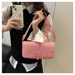 Détail du sac à bandoulière rose en tissu tissé avec boucle carrée et sangle assortie
