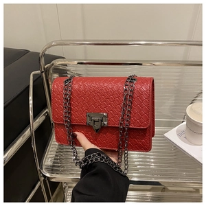 Gros plan détaillé d'un sac rouge à texture tissée avec bandoulière chaîne et fermoir