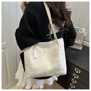 Detail of white lace tote bag featuring 3D butterfly embroidery and woven shoulder strap
