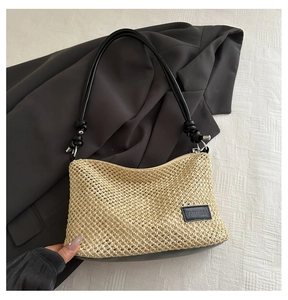 Détail d'un sac en paille tressé avec bandoulière en cuir noir et écusson logo