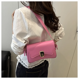 Pink faux leather shoulder bag with gold twist lock shown on white lace top