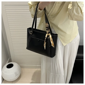 Detail of black PU tote bag with white contrast stitching and printed silk scarf handle