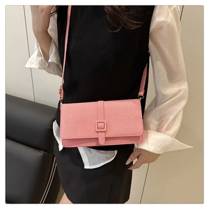 Détail de la texture en sergé rose et blanc d'un sac bandoulière à boucle carrée