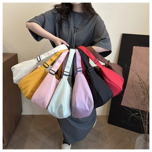 Variety of colorful canvas crescent crossbody bags shown together in a single lifestyle shot