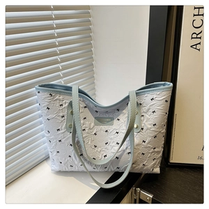 Detail der weißen Plissee-Tasche mit schwarzen Schleifen und hellblauen Tragegriffen
