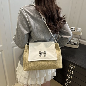 Straw woven shoulder bag with white flap and silver bow clasp worn by a model