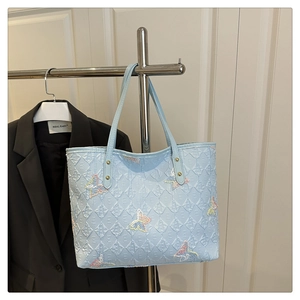 Détail du cabas bleu clair avec broderie papillon et textures gaufrées