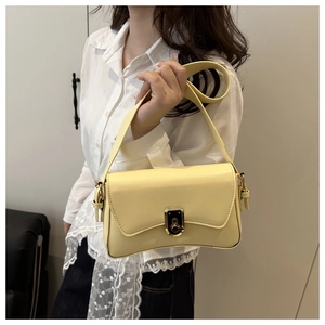 Detailed view of yellow faux leather crossbody bag with curved base and golden metal buckle