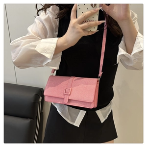 Sac bandoulière rose en tissu tressé avec boucle carrée présenté dans un décor de style