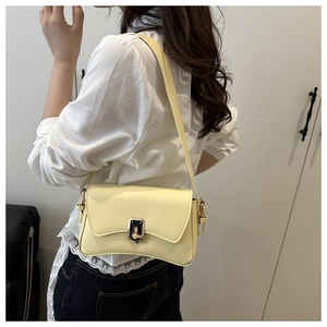 Detail of light yellow leather shoulder bag with chic metal buckle worn by model