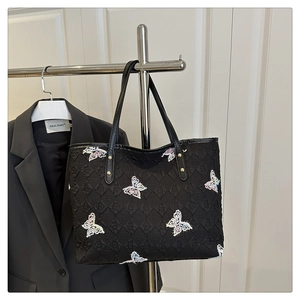 Détail de la broderie papillon sur le sac cabas noir avec jacquard et rivets dorés
