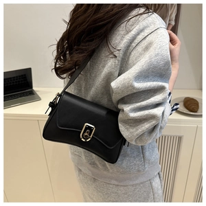 Detail view of black faux leather shoulder bag with a gold rectangular metal swivel lock