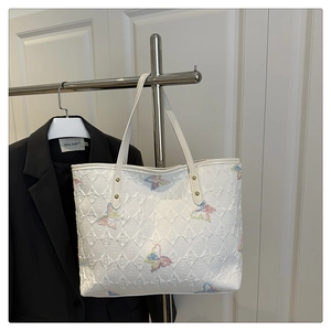 Détail du sac cabas blanc avec broderies de papillons colorés et motifs en relief