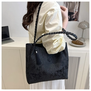 Detail of black jacquard tote bag with butterfly textures and elegant tassel charm
