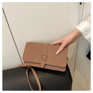 Vue détaillée de la texture tissée marron et de la sangle décorative sur le sac à rabat